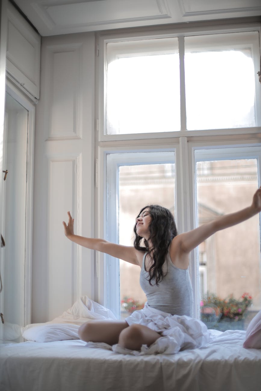 photo of woman in gray tank top while sitting on bed