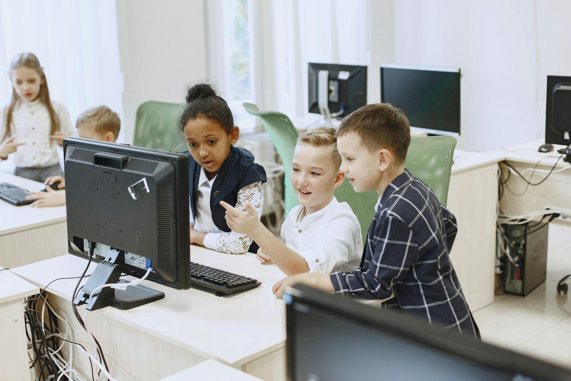children taking it classes looking at a computer screen. AI in the classroom. 