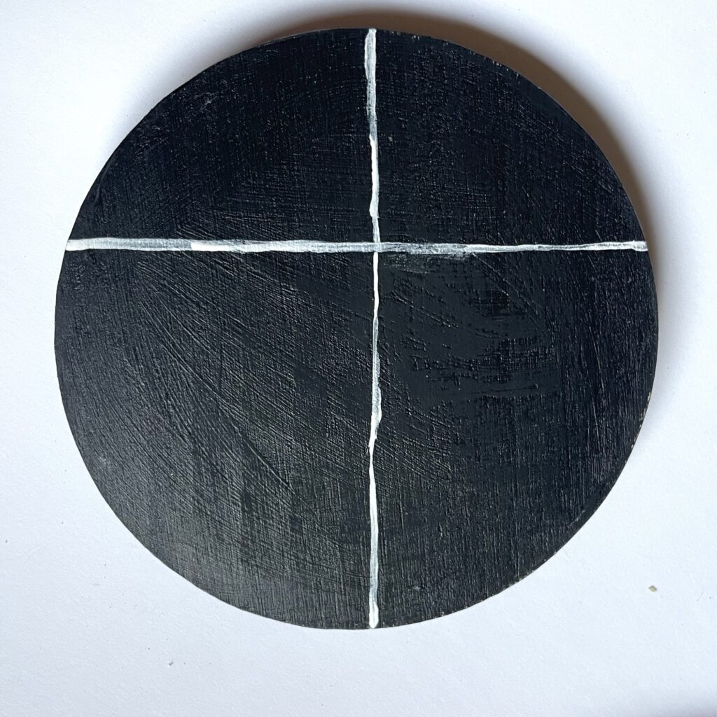 A black coaster with a with crossed lines through it. 