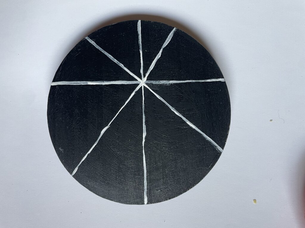 A black coaster with two sets of crossed lines.