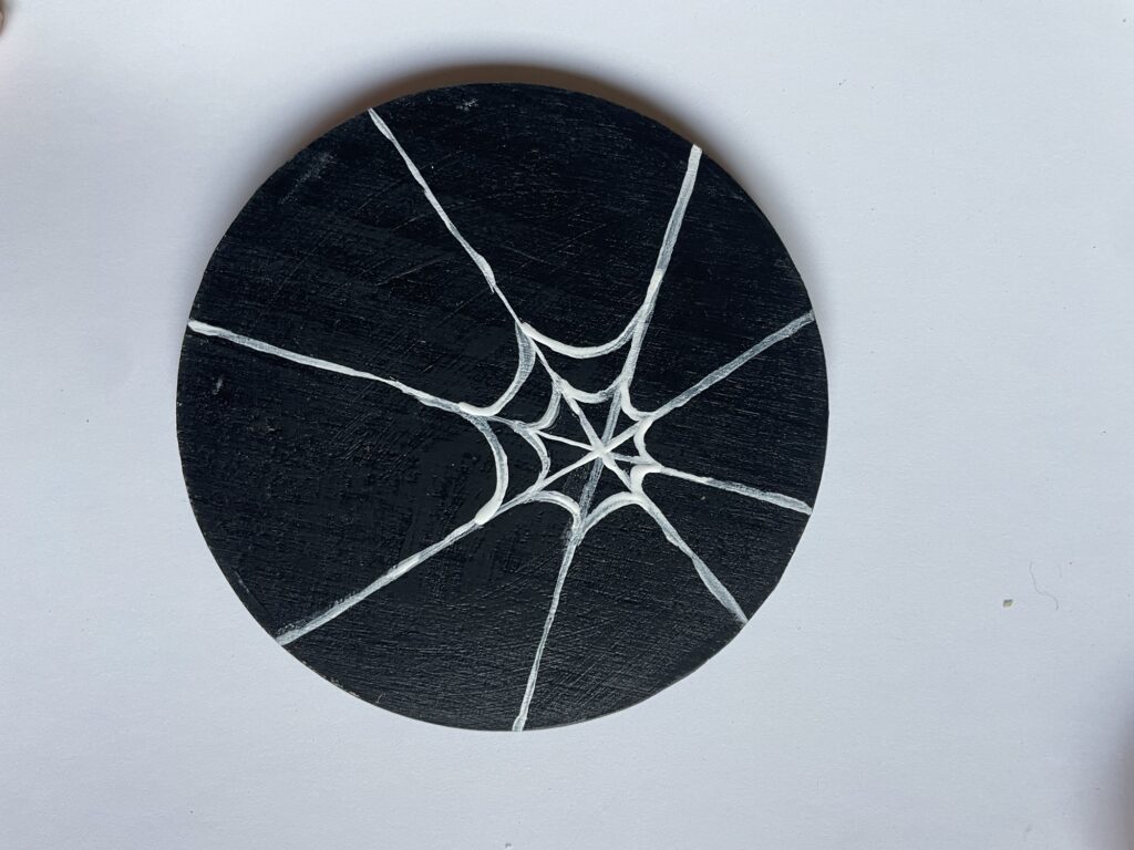 A black coaster with white lines connecting the crossed lines. 