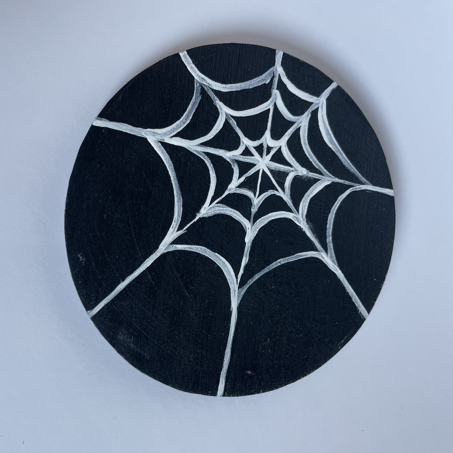A black and white spider’s web Halloween coaster. 