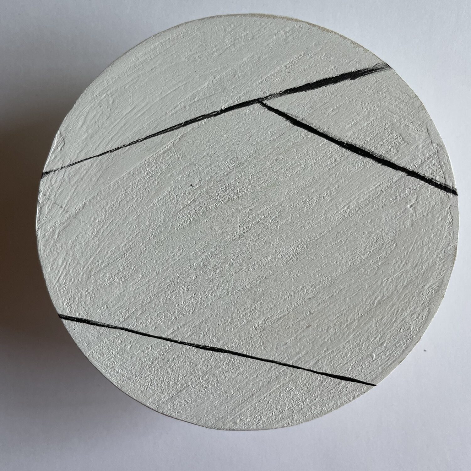 A white coaster with three black angled lines on it. 