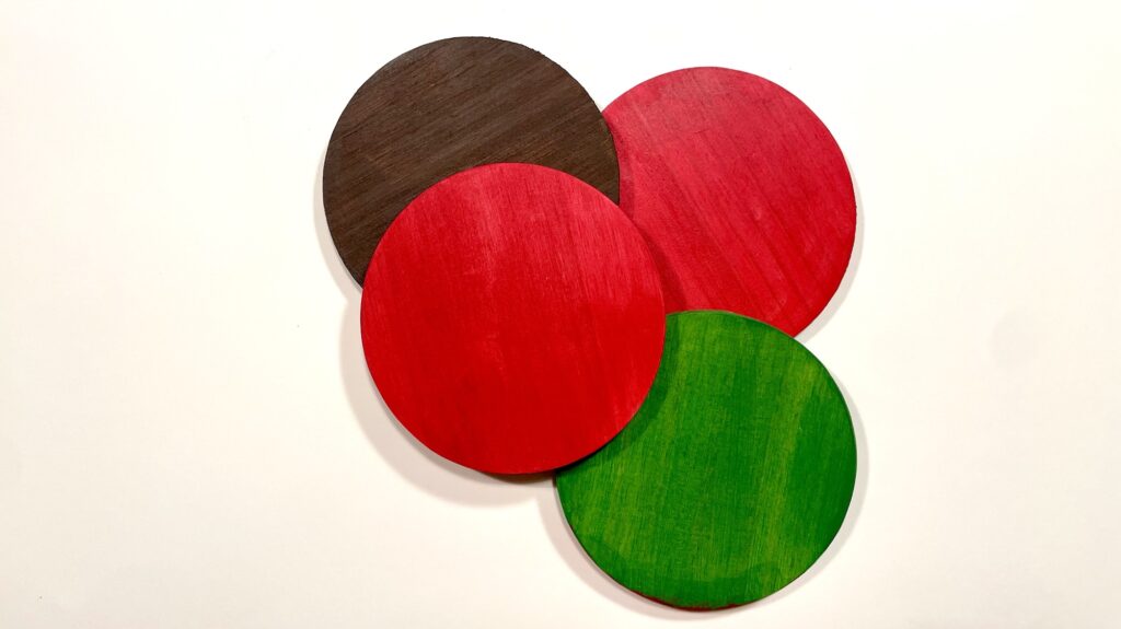Painted round coasters in red, green, and brown. 
