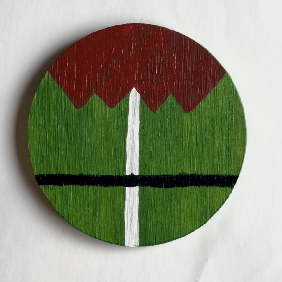 Green coaster with white and black intersecting lines with a red elf collar on the top. 