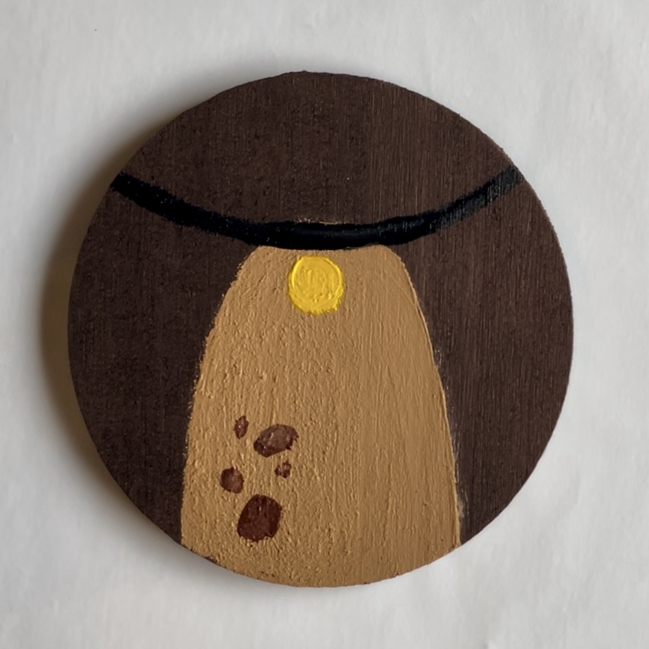 A yellow circle and brown spots added over the tan oval on the brown coaster. 