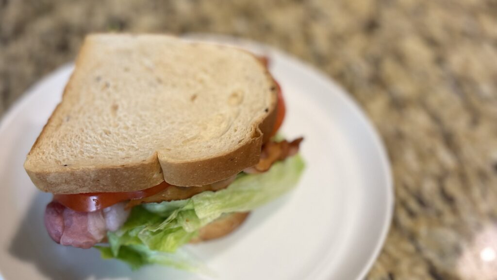 BLT sandwich with low-carb bread on a white platter. One of the biggest Keto Diet Game Changers.