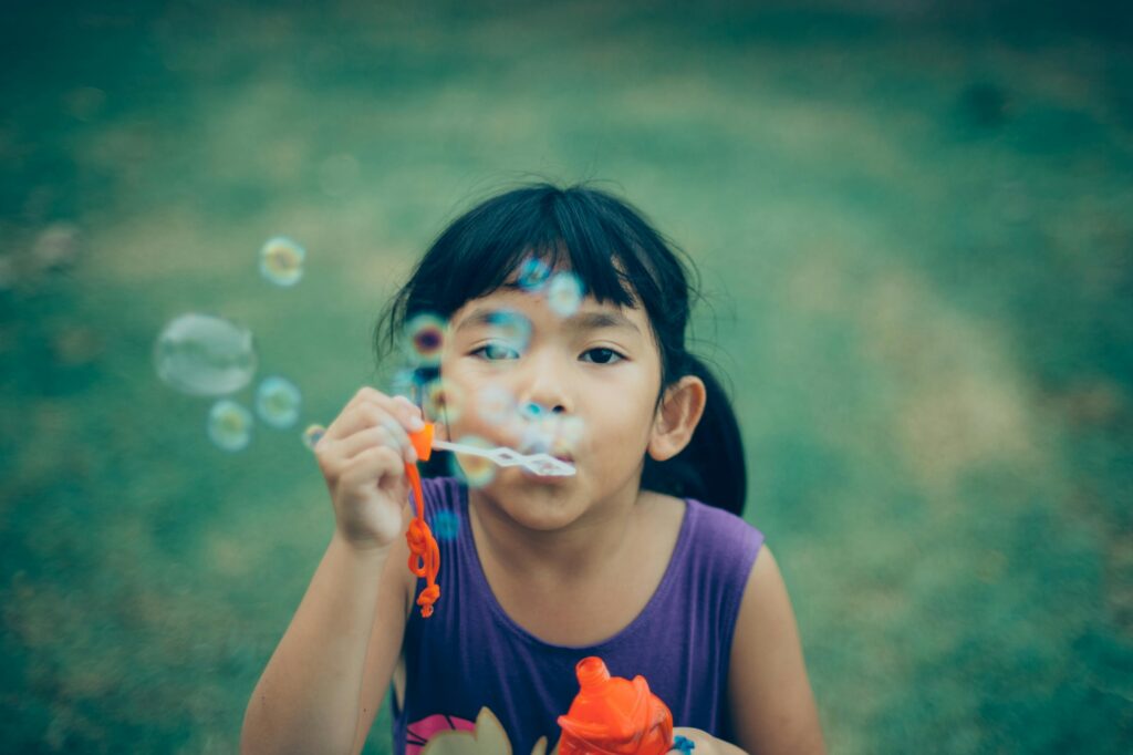 Girl blowing bubbles in a green summer field. 