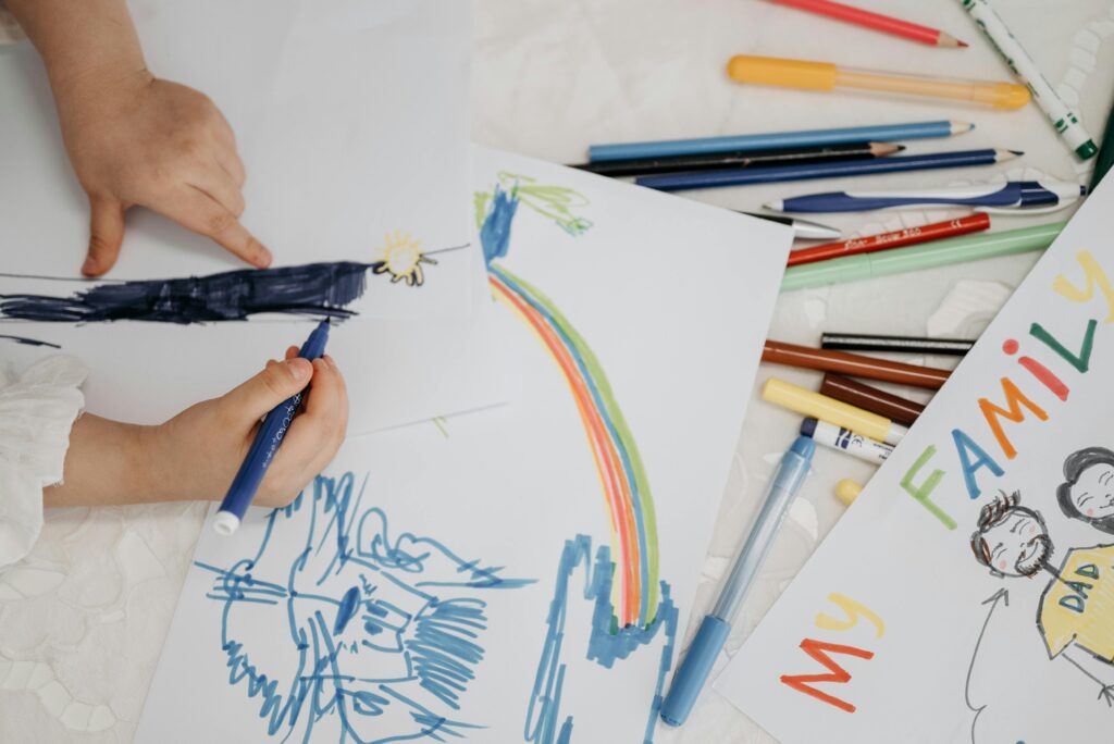 Coloring is one to-do for the dummer.  A kid drawing a blue lion with paper and pencils everywhere. 
