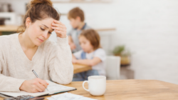 A woman using a realistic home budgeting system to make life easier. She is sitting at a table with a budget planner.
