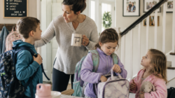 Mom helping three kids get ready before school.