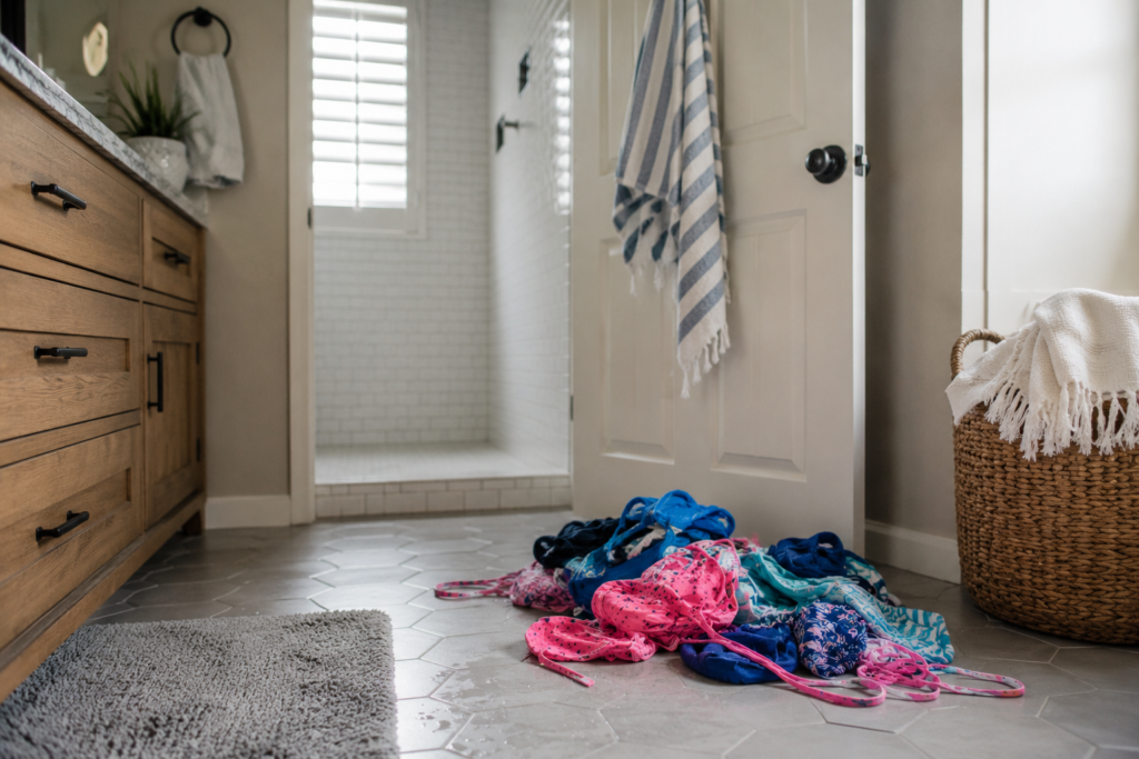 A pile of wet bathing suits on the bathroom floor.